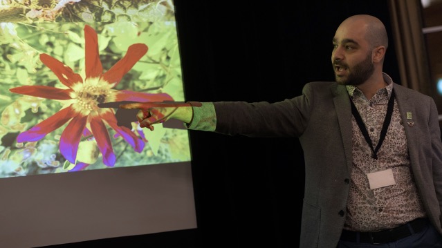 Education & Youth man point at screen with pollinator on flower.